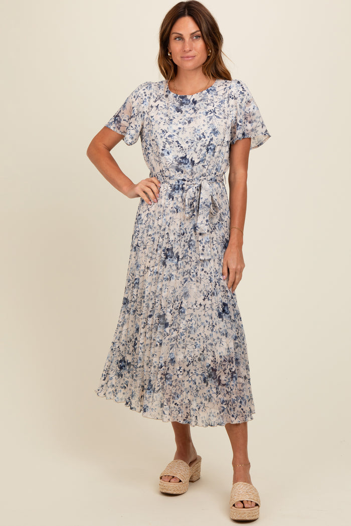 woman wearing a floral print midi dress in shades of blue with short sleeves and a tie waist detail