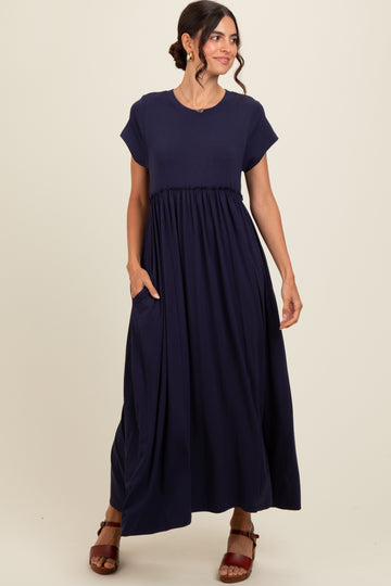 woman wearing a navy blue maxi dress with short sleeves and a gathered waist, featuring pockets