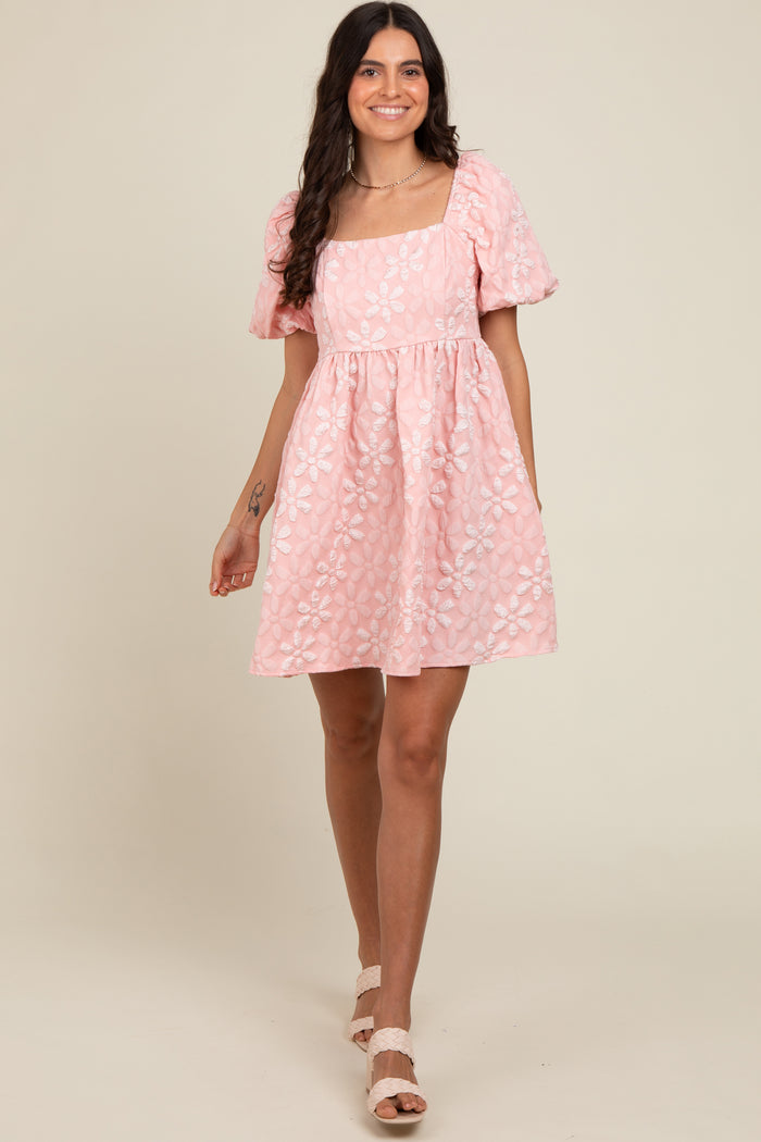 woman wearing a pink puff sleeve square neck dress with floral embroidery and a flared skirt
