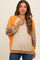 woman wearing an orange and beige long sleeve maternity sweatshirt with plaid detail and a visible baby bump