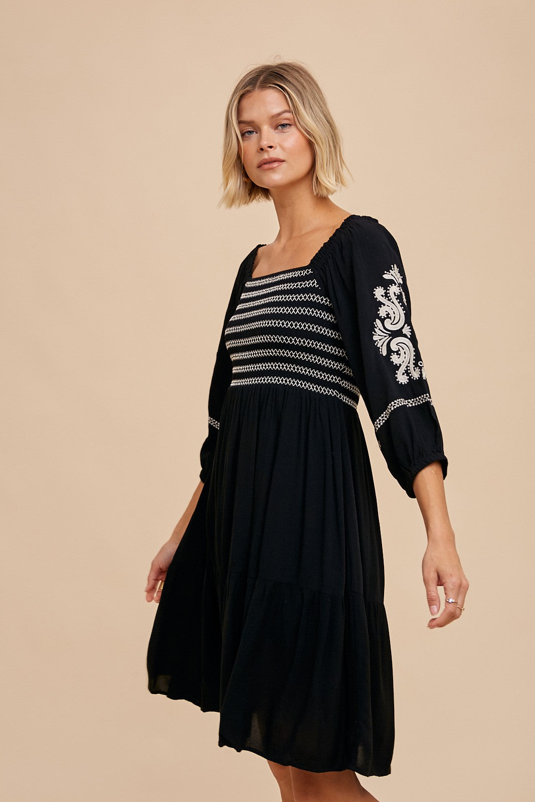 woman wearing a black tiered dress with striped and embroidered detailing on the sleeves