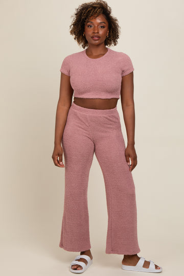 woman wearing a pink cropped knit top and matching wide-leg pants, styled with white slides