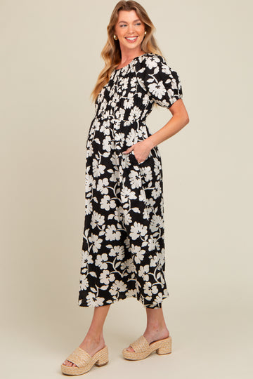 woman wearing a black and white floral maternity dress with puff sleeves and pockets, highlighting her baby bump