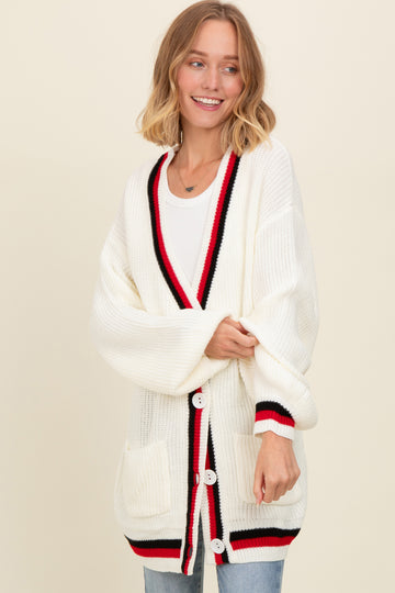 woman wearing an oversized white cardigan with red and black trim and pockets, styled with a casual look