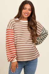 woman wearing a striped maternity sweatshirt with long sleeves in earthy tones and smiling at the camera