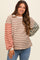 woman wearing a striped maternity sweatshirt with long sleeves in earthy tones and smiling at the camera