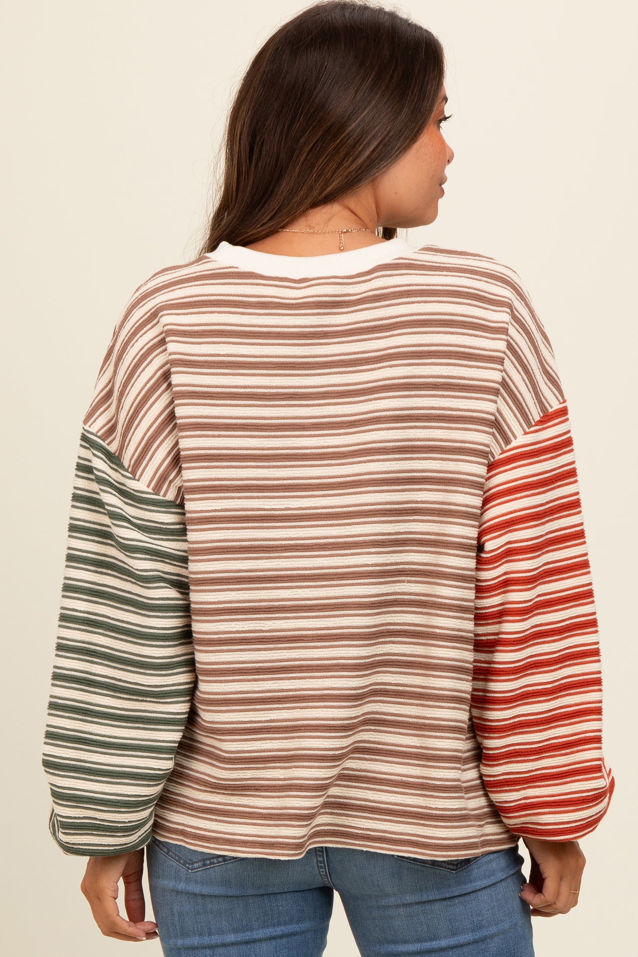 woman wearing a striped maternity top with long, colorful sleeves and a relaxed fit