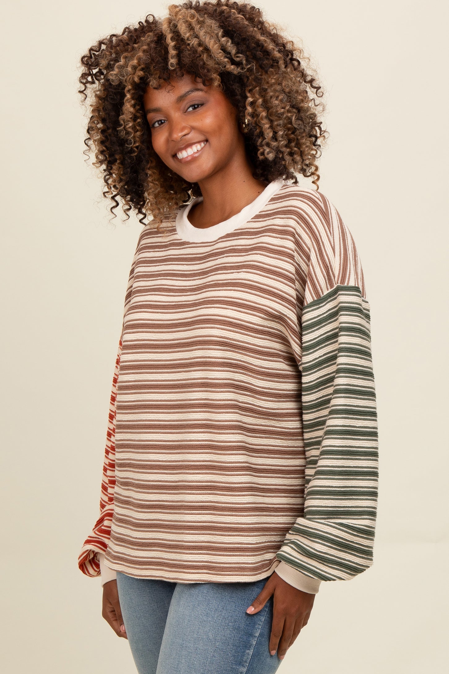 woman wearing a multicolored striped long sleeve top with a round neckline and a relaxed fit