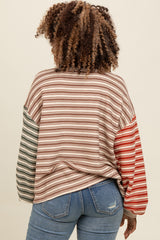 woman wearing a multicolor striped long sleeve top with green and red accents, paired with blue jeans