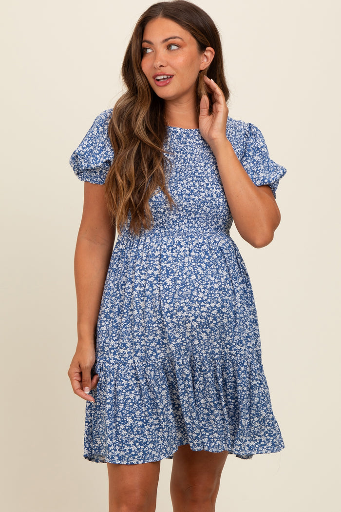 woman wearing a blue floral maternity dress with short puff sleeves and a tiered skirt