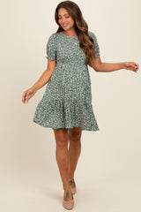 woman wearing a green floral maternity dress with short puff sleeves and a tiered skirt, showcasing a baby bump