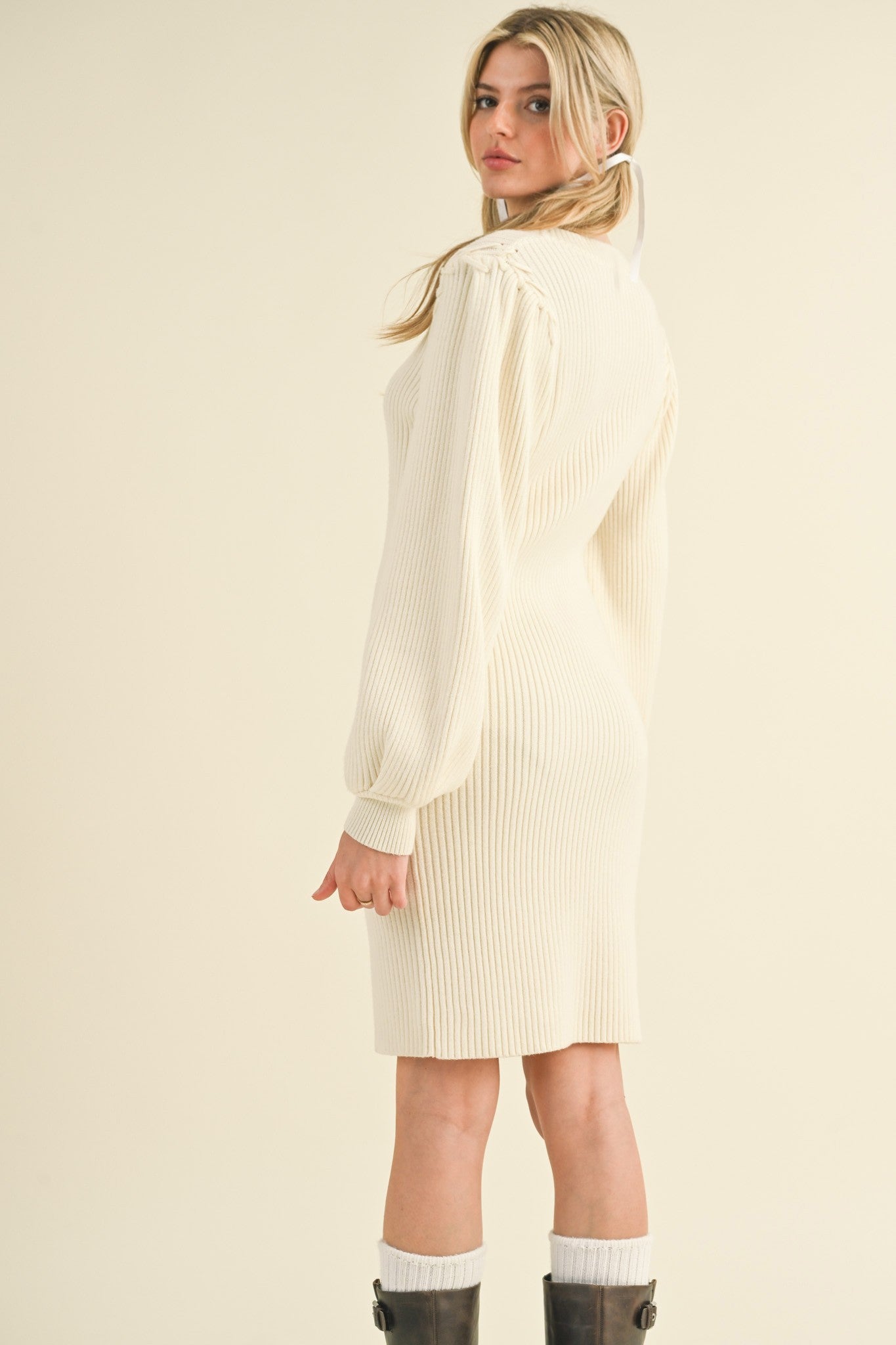 woman wearing a cream ribbed long sleeve sweater dress with puff sleeves and a fitted silhouette