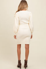 woman wearing a cream ribbed maternity dress with long puff sleeves, showing a fitted style from the back