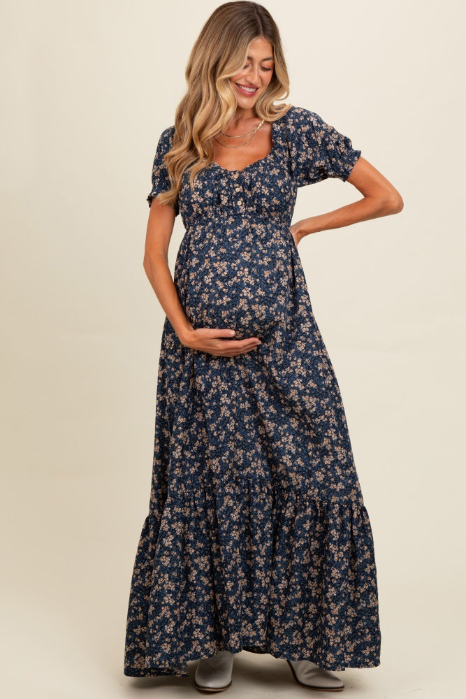 woman wearing a navy blue floral maternity maxi dress, smiling and cradling her baby bump