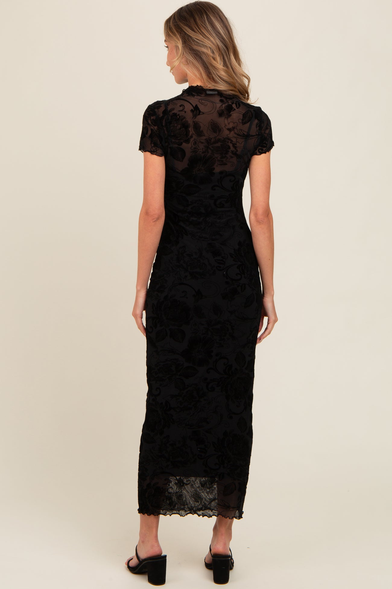 woman wearing a black floral lace maxi dress with short sleeves and a fitted silhouette, viewed from the back