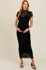 woman wearing a black floral lace maternity dress with a fitted silhouette and short sleeves, holding her baby bump