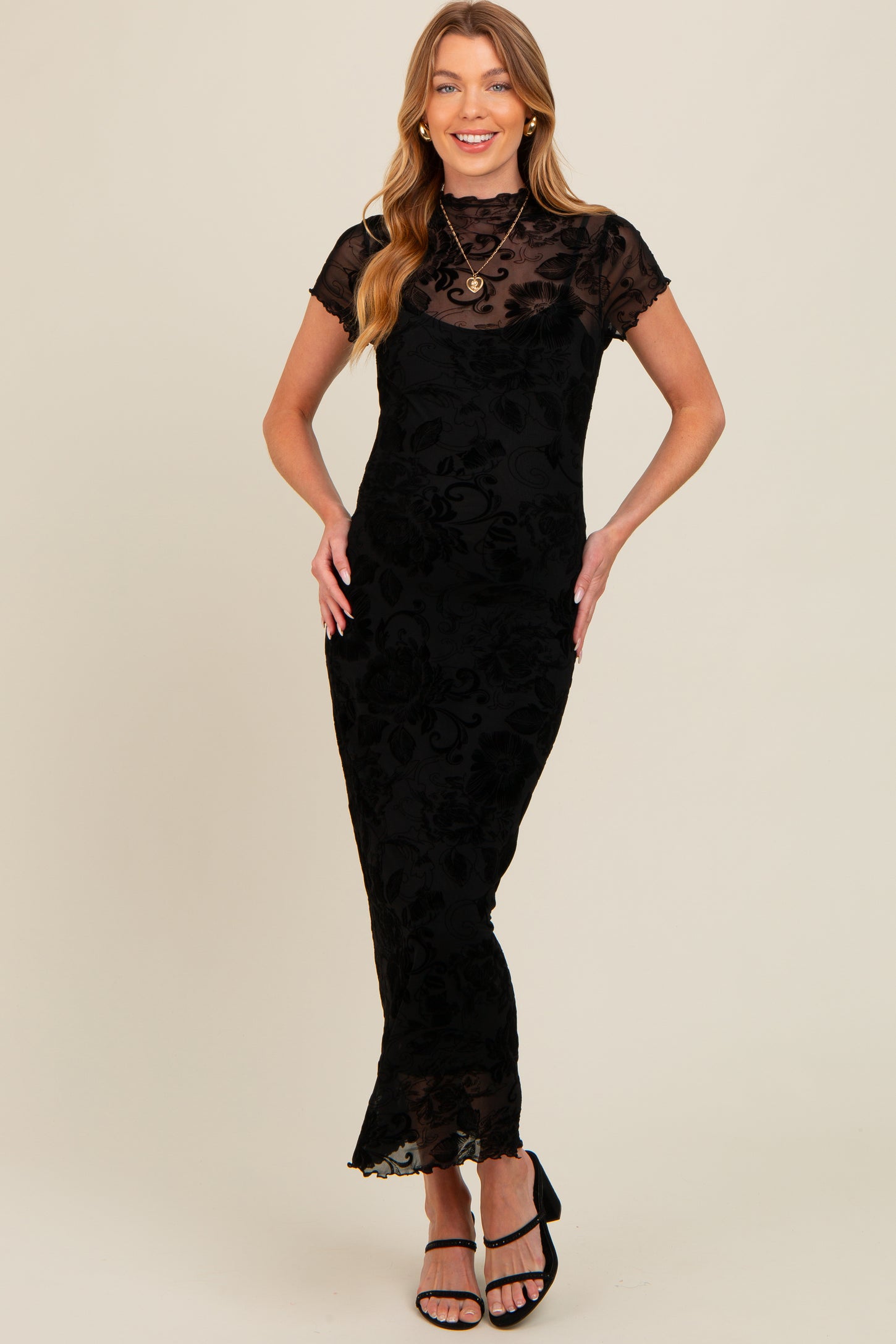 woman wearing a black maternity dress with floral lace overlay and short sleeves, styled for a formal occasion