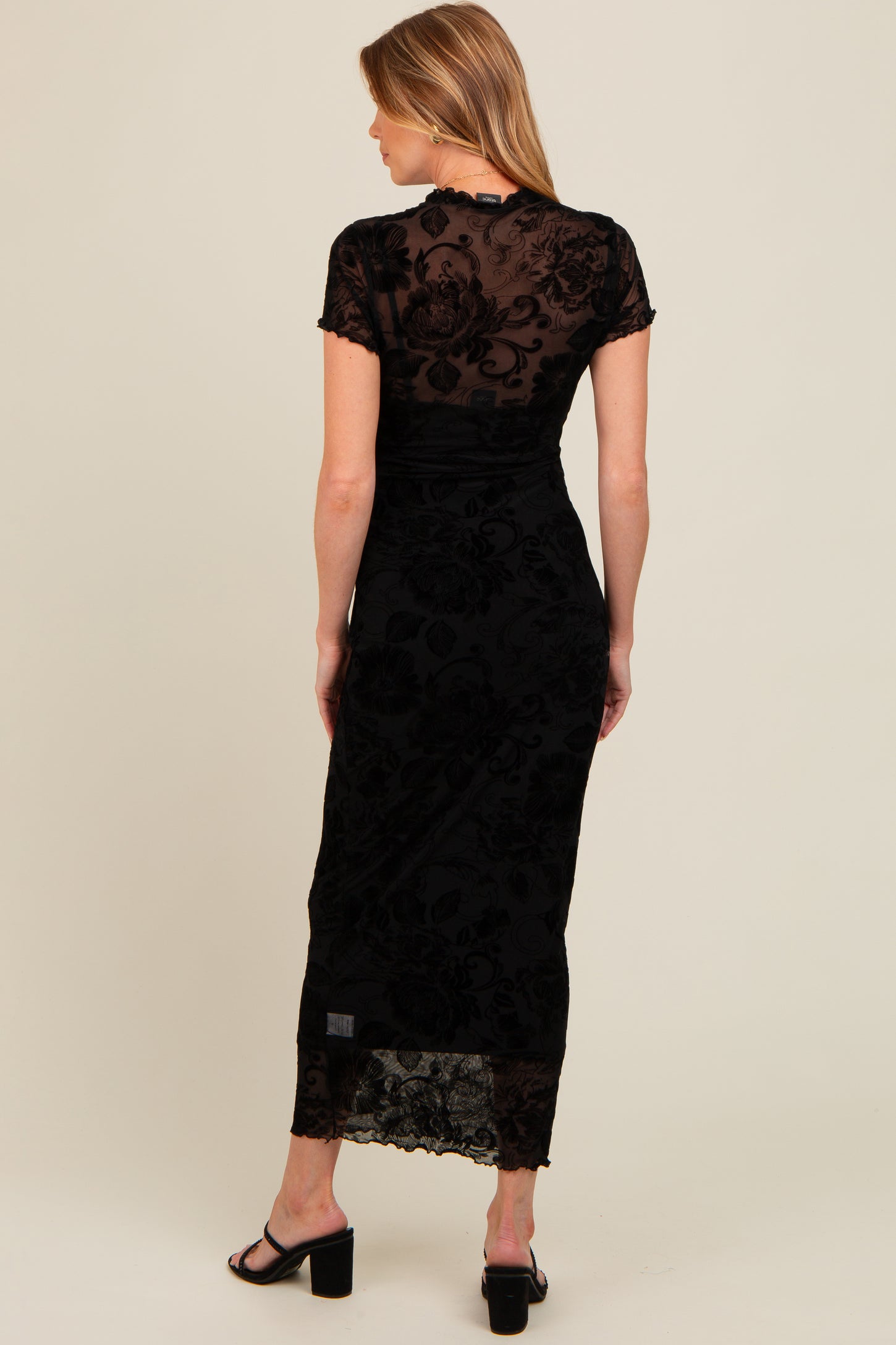 woman wearing a black lace maternity dress with short sleeves and a fitted silhouette, showcasing a stylish back view