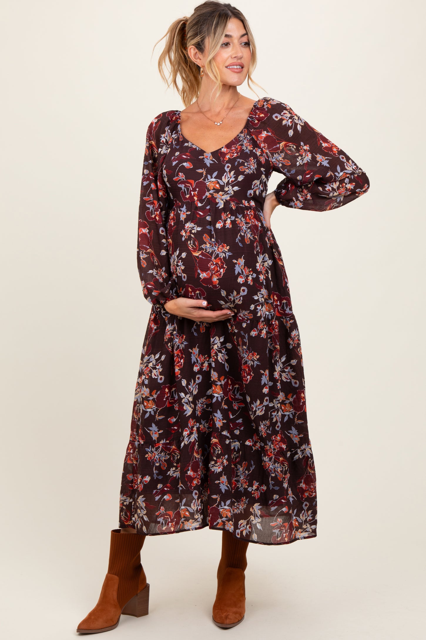 woman wearing a burgundy floral maternity maxi dress with long sleeves and holding her baby bump