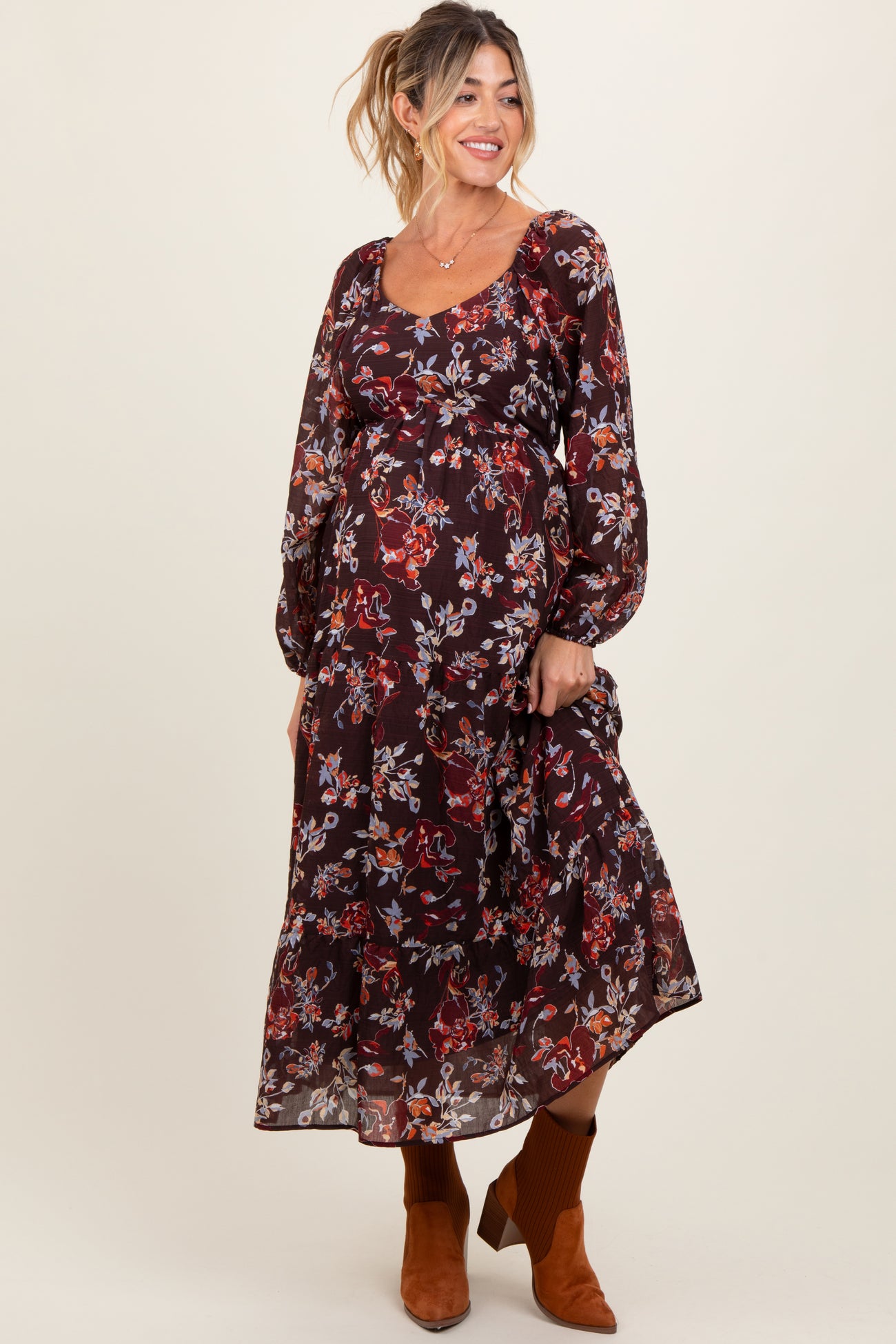 woman wearing a burgundy floral print maternity maxi dress with long sleeves and a baby bump visible