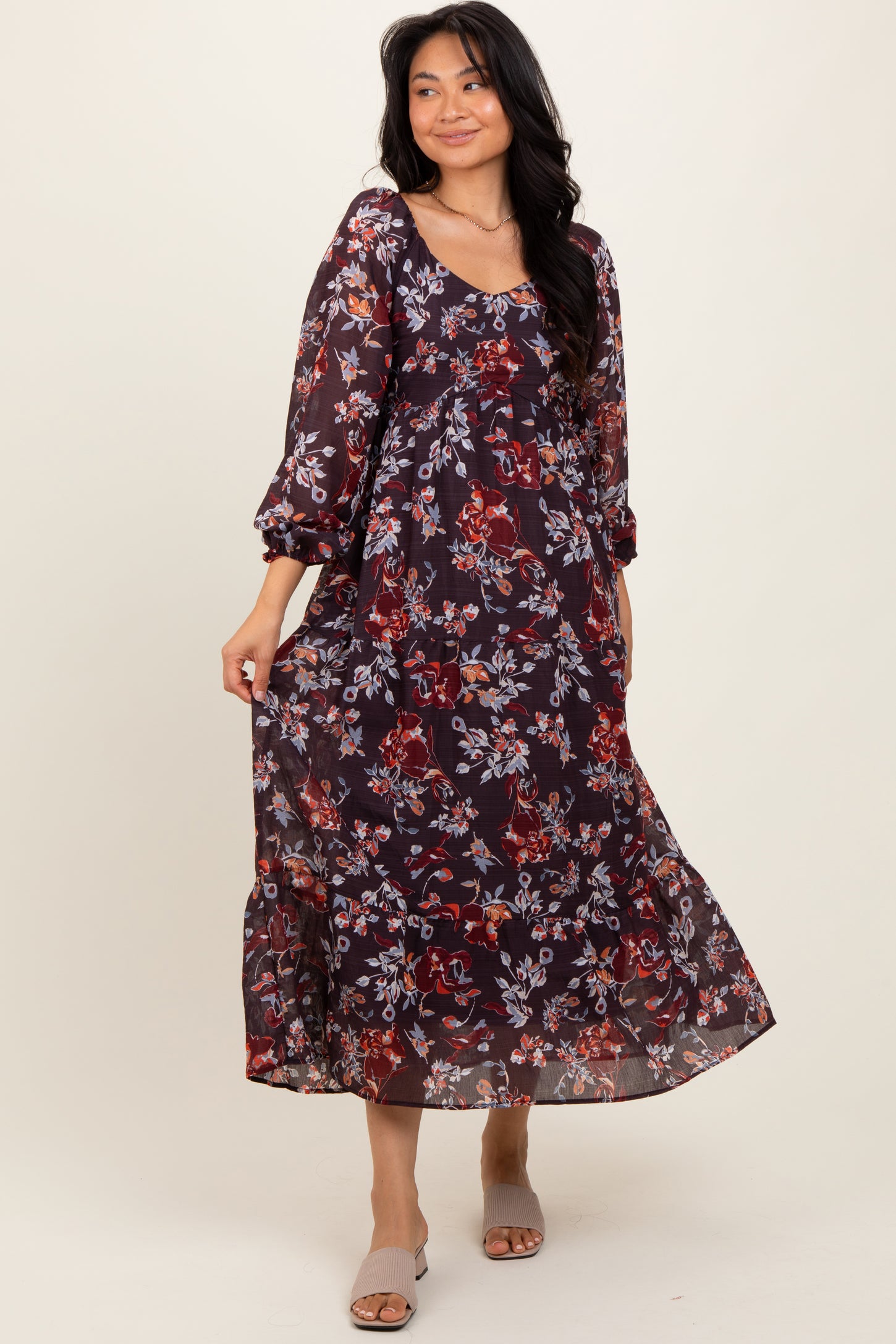 woman wearing a burgundy floral maxi dress with long sleeves and a tiered skirt