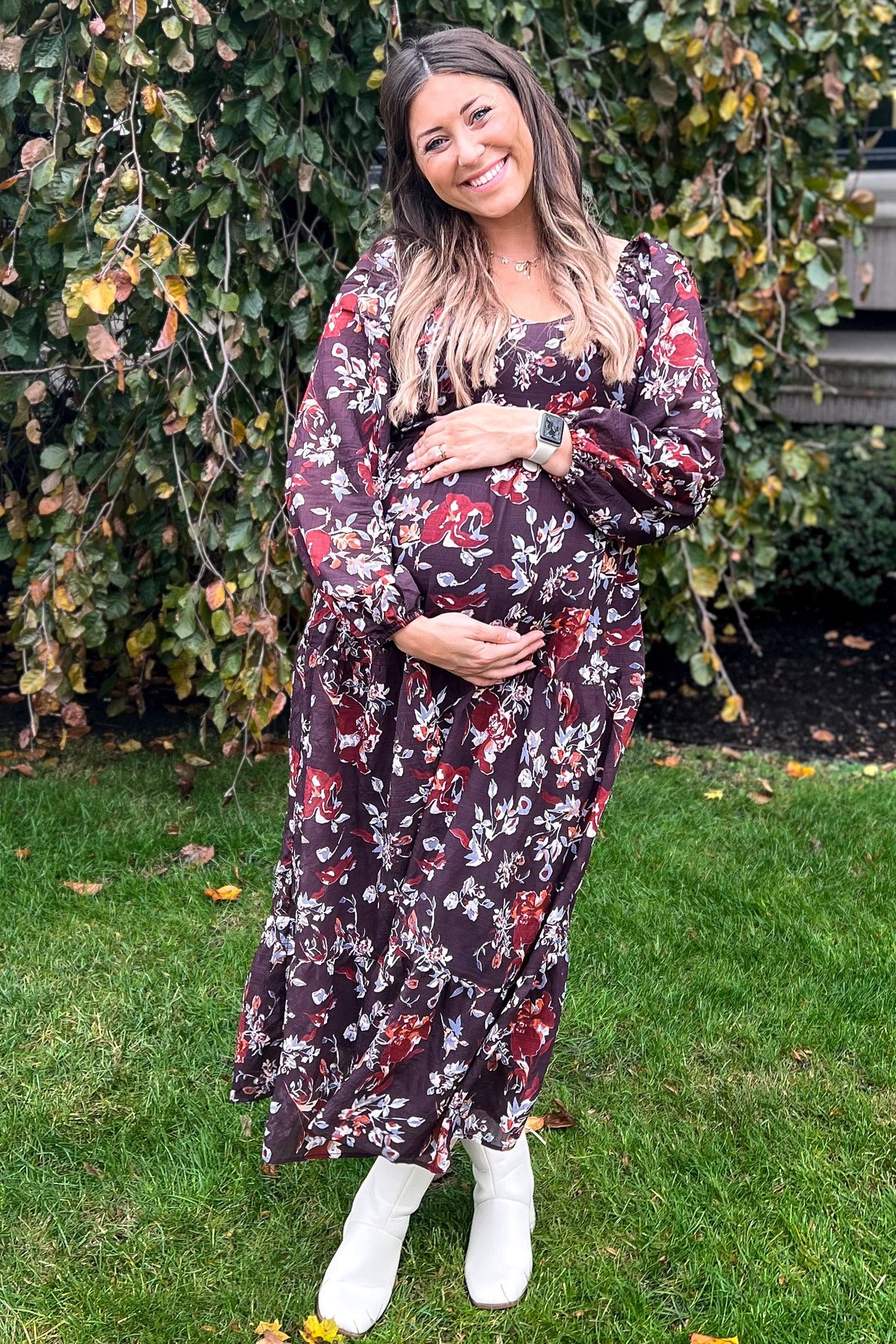 woman wearing a floral burgundy maternity maxi dress and holding her baby bump