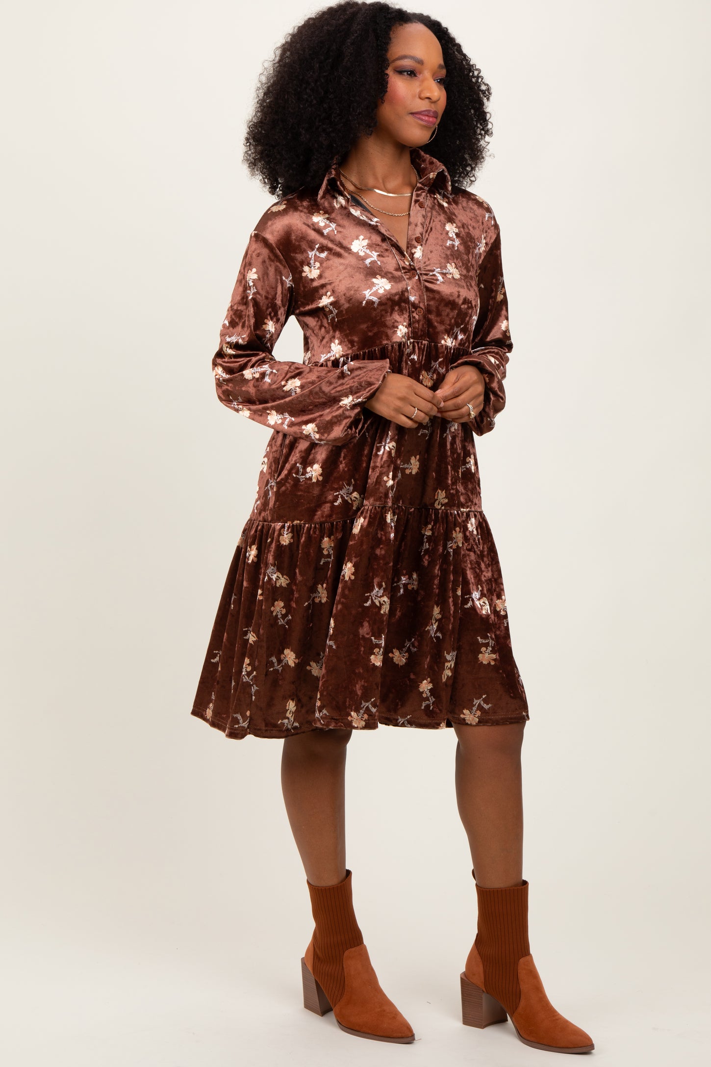 woman wearing a brown velvet long sleeve dress with floral embroidery and a tiered skirt, paired with ankle boots
