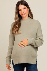 woman wearing a light green maternity sweater and holding her baby bump