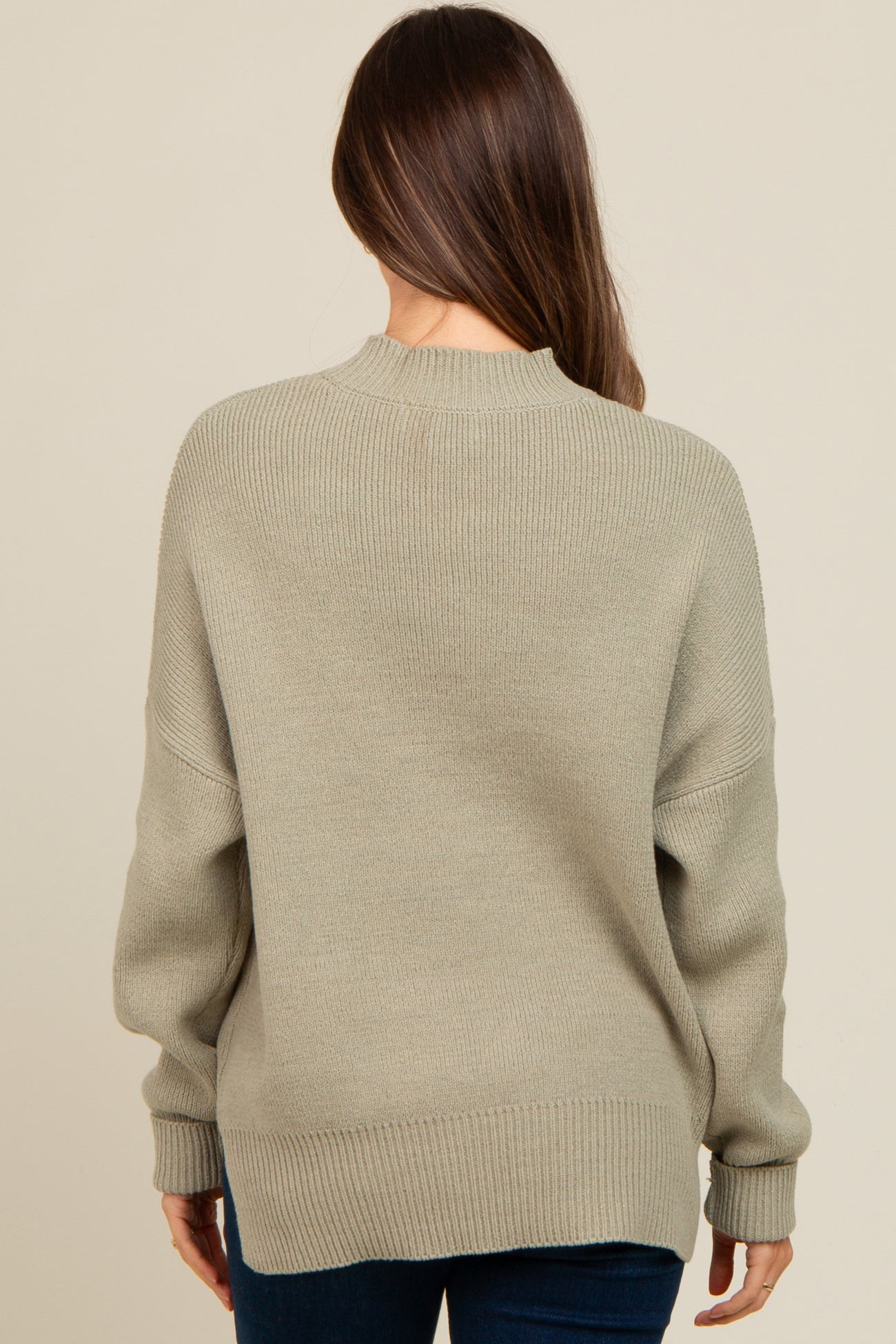 woman wearing a light green oversized maternity sweater, viewed from the back