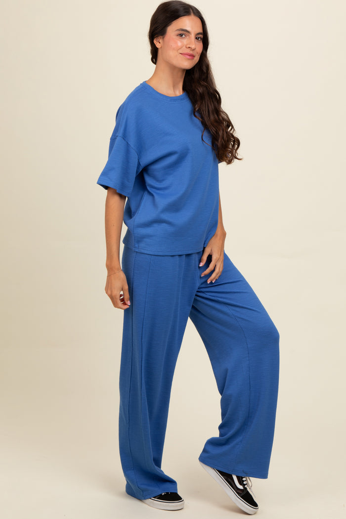 woman wearing a loose-fitting blue ribbed top and matching wide-leg pants, posed against a neutral background