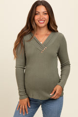 woman wearing a green ribbed maternity top with a v-neck and button details, showing her baby bump