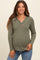 woman wearing a green ribbed maternity top with a v-neck and button details, showing her baby bump