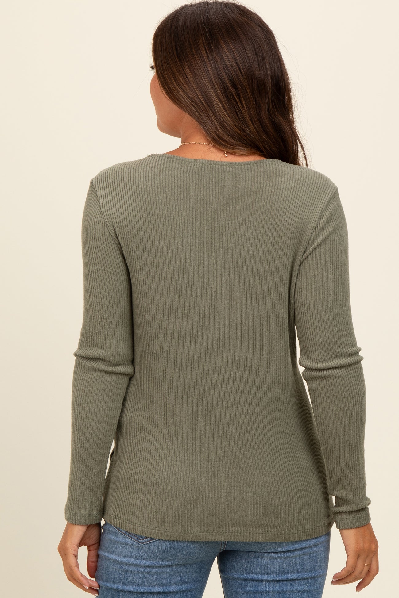 woman wearing a green ribbed maternity top, seen from the back, with long sleeves and a relaxed fit