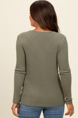 woman wearing a green ribbed maternity top, seen from the back, with long sleeves and a relaxed fit