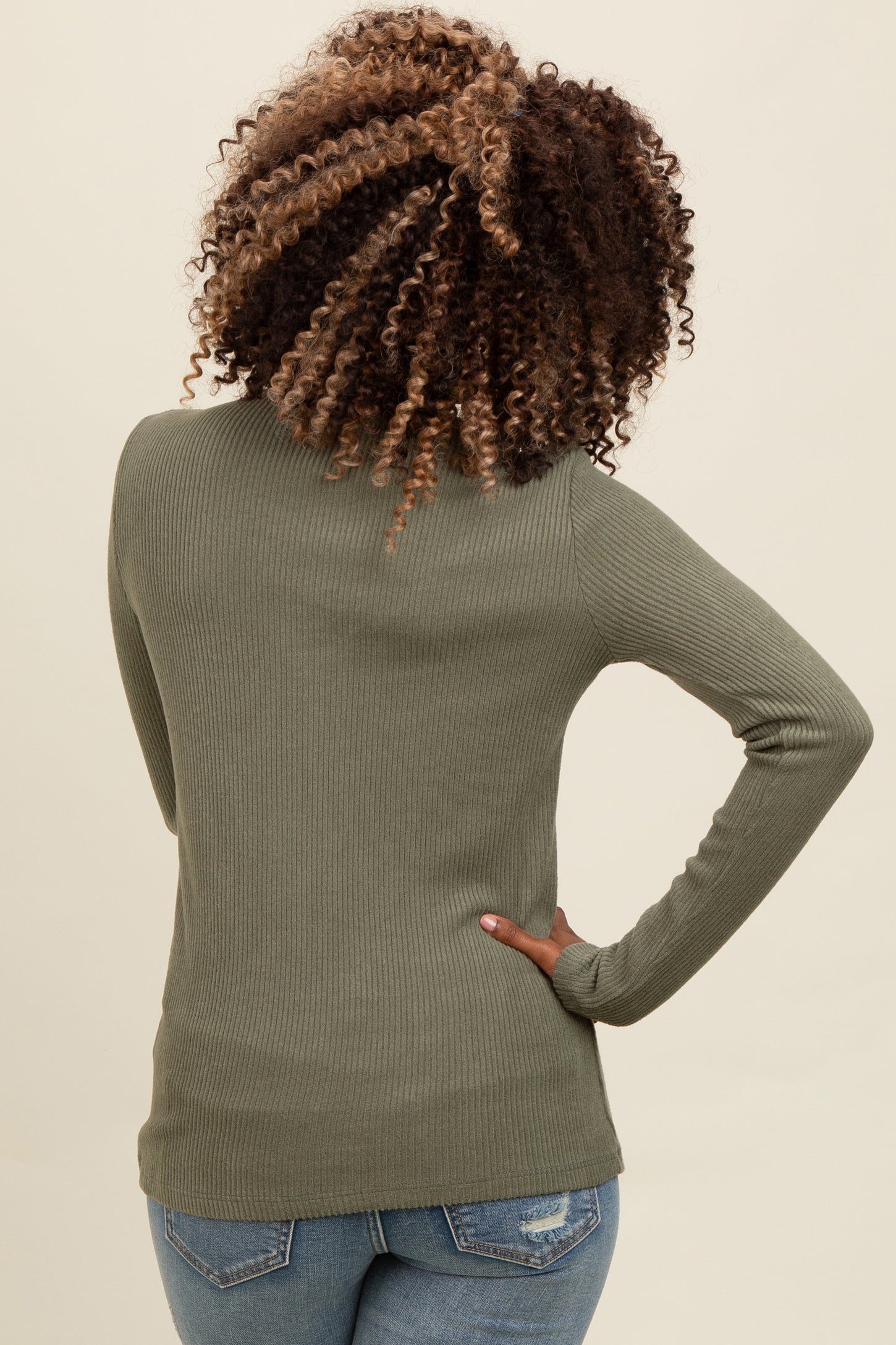 woman wearing an olive green ribbed long sleeve top, view from the back, paired with blue jeans