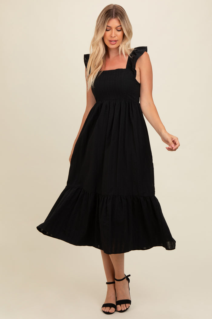 woman wearing a black midi dress with ruffle straps and a tiered skirt