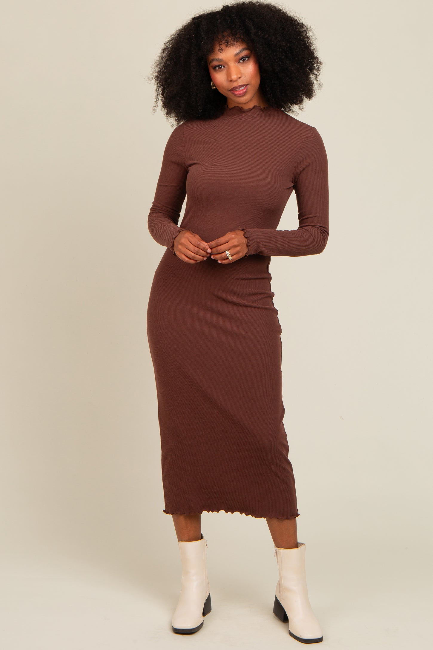 woman wearing a brown long sleeve ribbed midi dress with a scalloped hem and white ankle boots