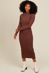 woman wearing a brown long sleeve ribbed midi dress and white ankle boots, smiling with hands on her hips