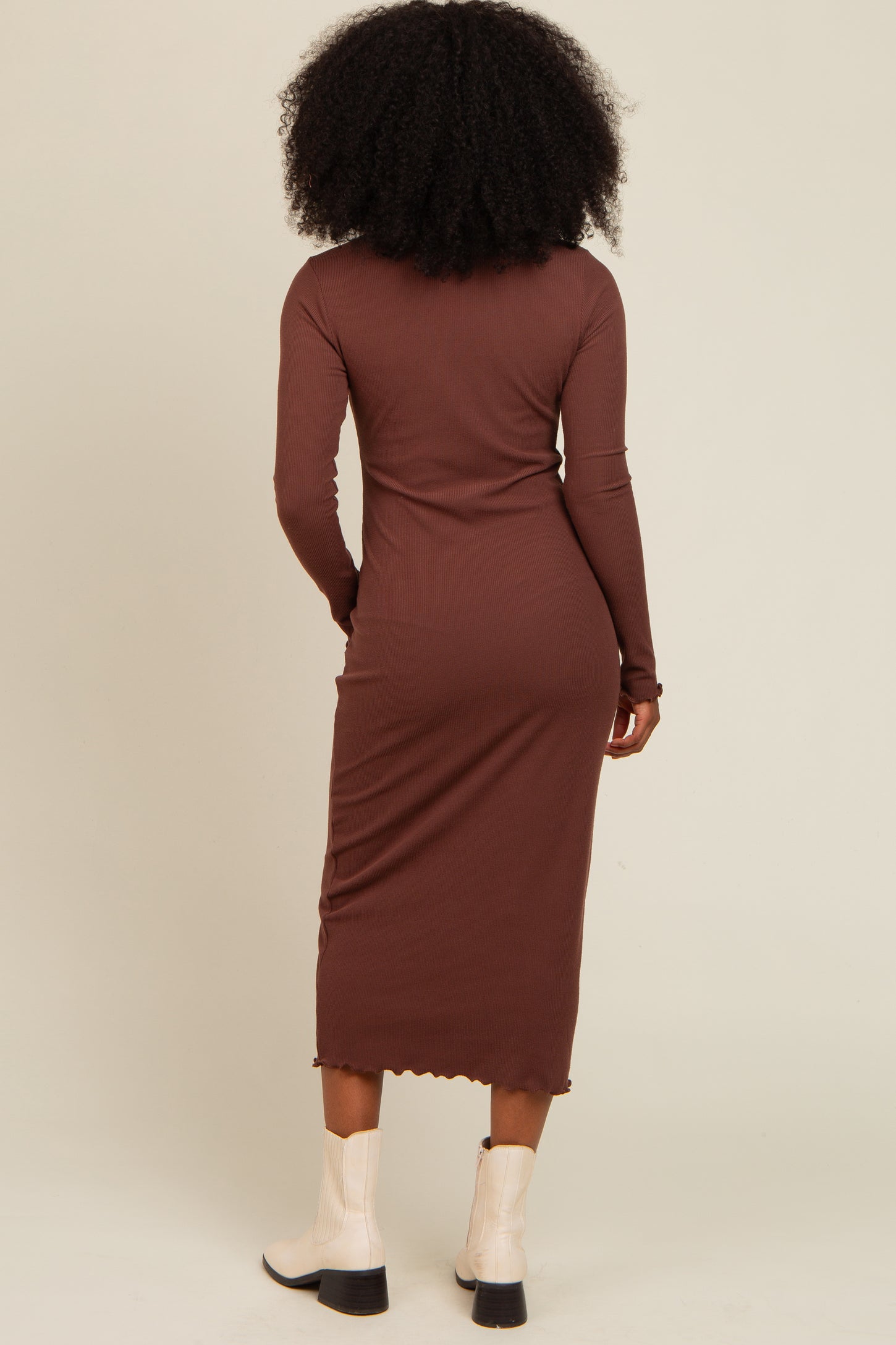 woman wearing a brown ribbed long sleeve midi dress, standing with her back to the camera, paired with white ankle boots