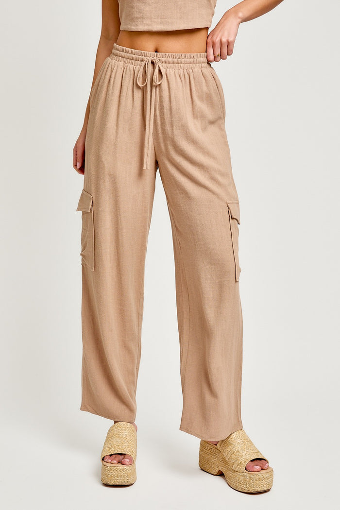 woman wearing beige cargo pants with a drawstring waist and side pockets, paired with gold platform sandals