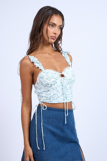 woman wearing a light blue floral crop top with ruffled straps and a tie-up detail at the back