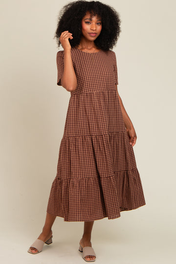 woman wearing a brown gingham tiered midi dress with short sleeves and a relaxed fit