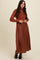 woman wearing a rust ribbed long sleeve knit top with a flowy brown maxi skirt