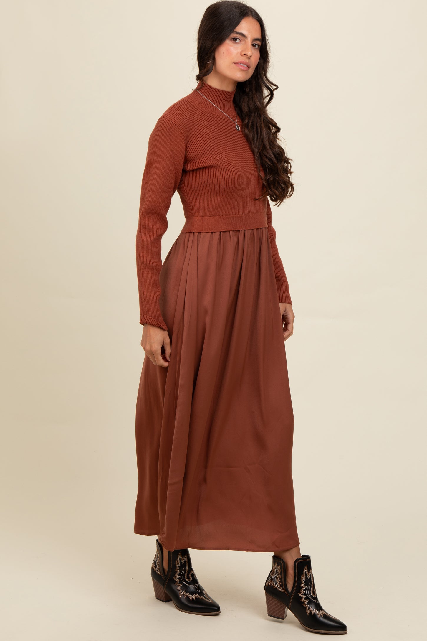 woman wearing a rust ribbed long sleeve crop top with a brown flowy maxi skirt and black ankle boots