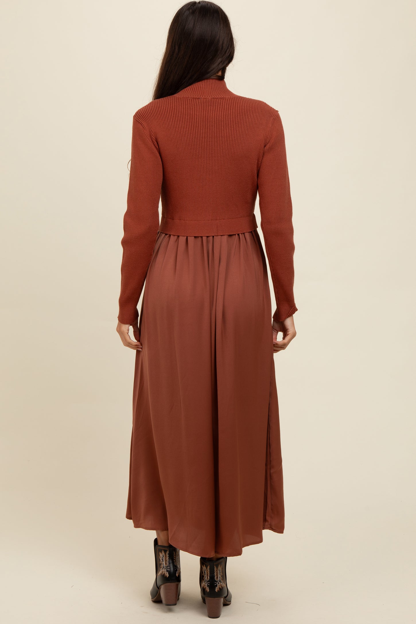 woman wearing a rust long sleeve ribbed top with a flowy maxi skirt, viewed from the back