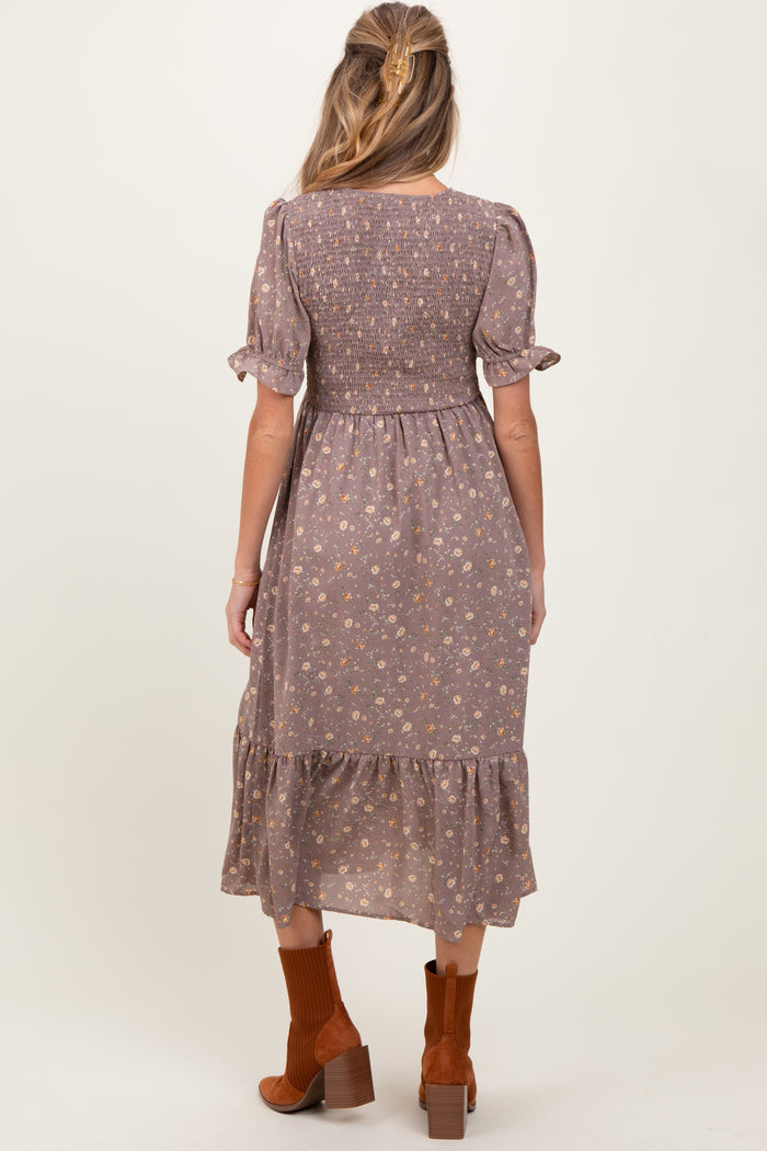 woman wearing a floral print maternity dress with short sleeves and a tiered hem, showing a baby bump