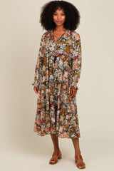 woman wearing a floral long sleeve midi dress with a v-neck and ruffled cuffs, standing on a light background