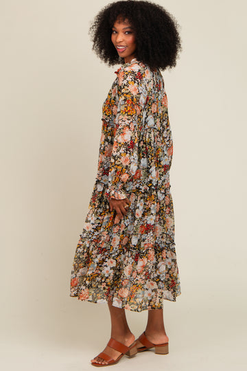 woman wearing a long floral print dress with tiered ruffles and bell sleeves, standing and smiling sideways