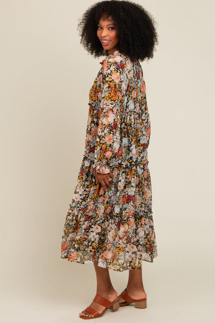woman wearing a long floral print dress with tiered ruffles and bell sleeves, standing and smiling sideways