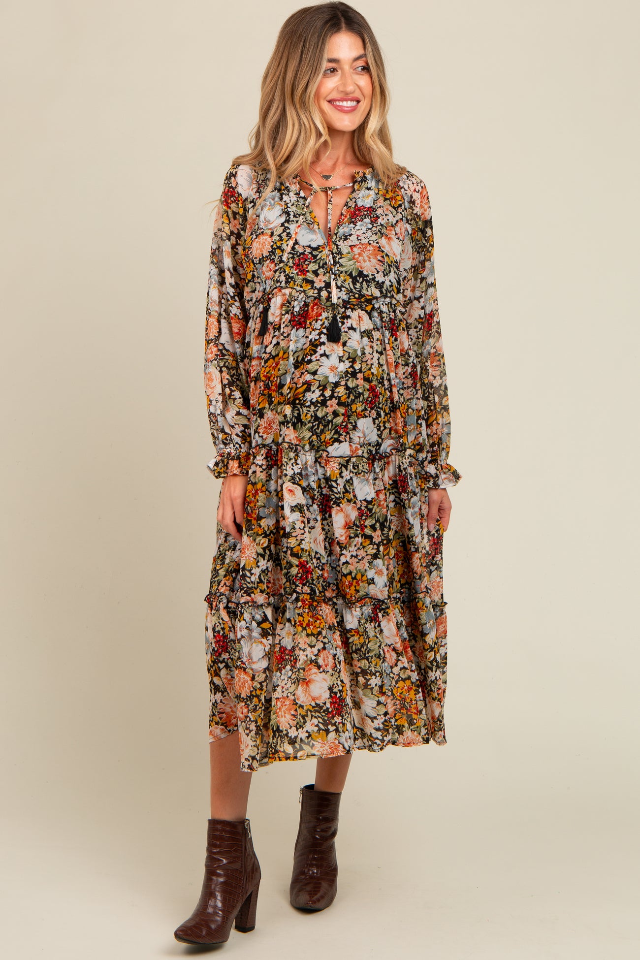 woman wearing a floral maternity dress with long sleeves and tiered skirt, showcasing her baby bump